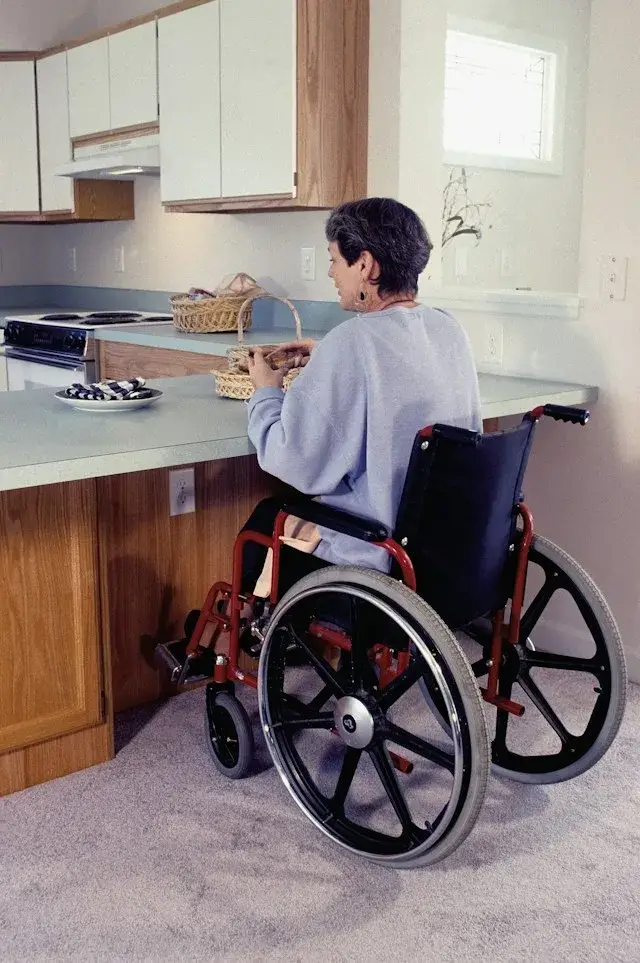 Women in wheelchair in her kitchen holding bread